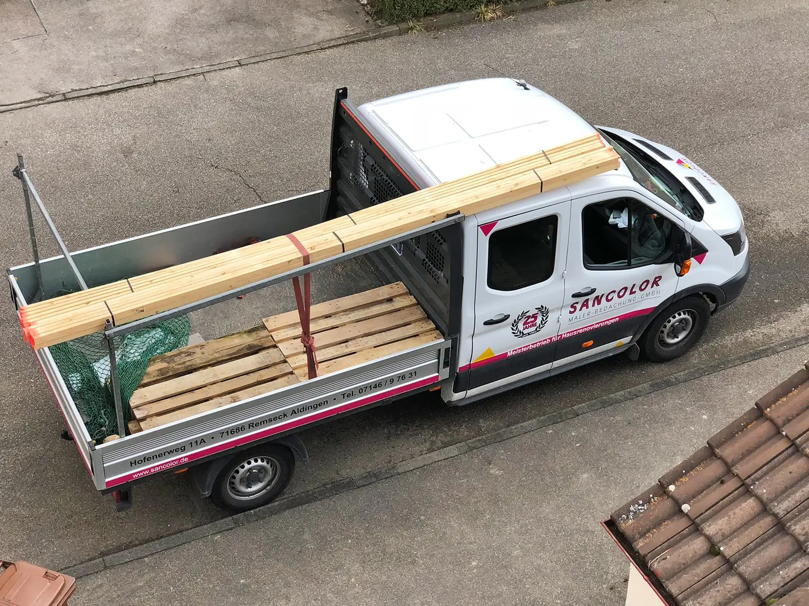 Sancolor Transportfahrzeug mit Holzladung auf Parkplatz